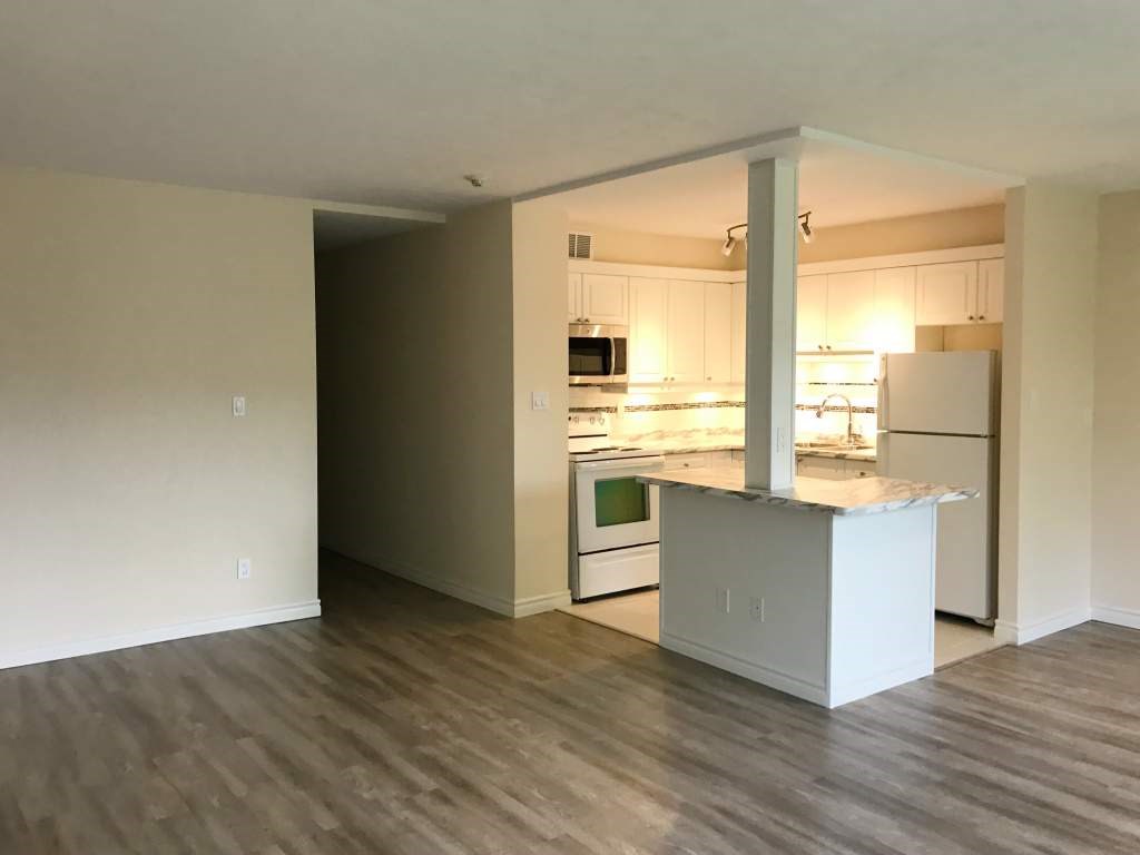 A kitchen with a white island and wooden floors.