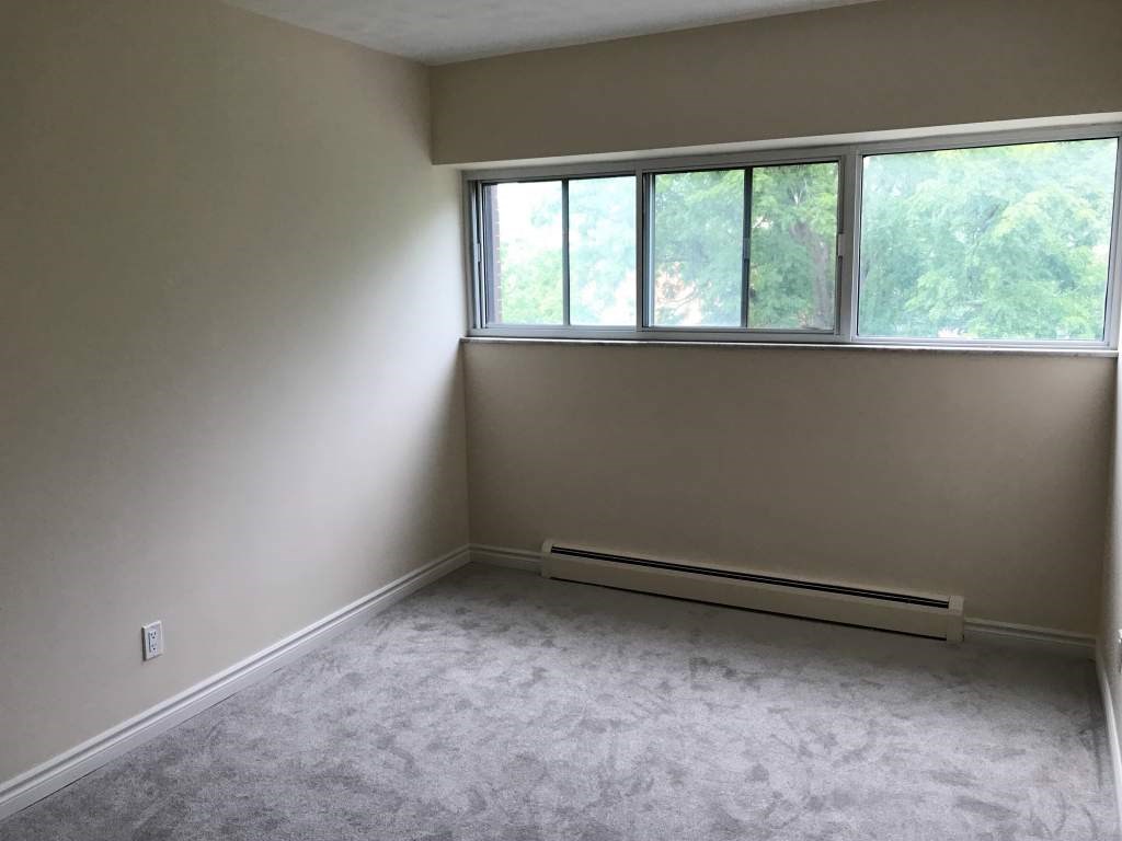 A room with a carpeted floor and a window.