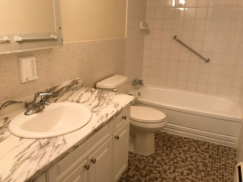 A white toilet sits next to a sink in a bathroom.