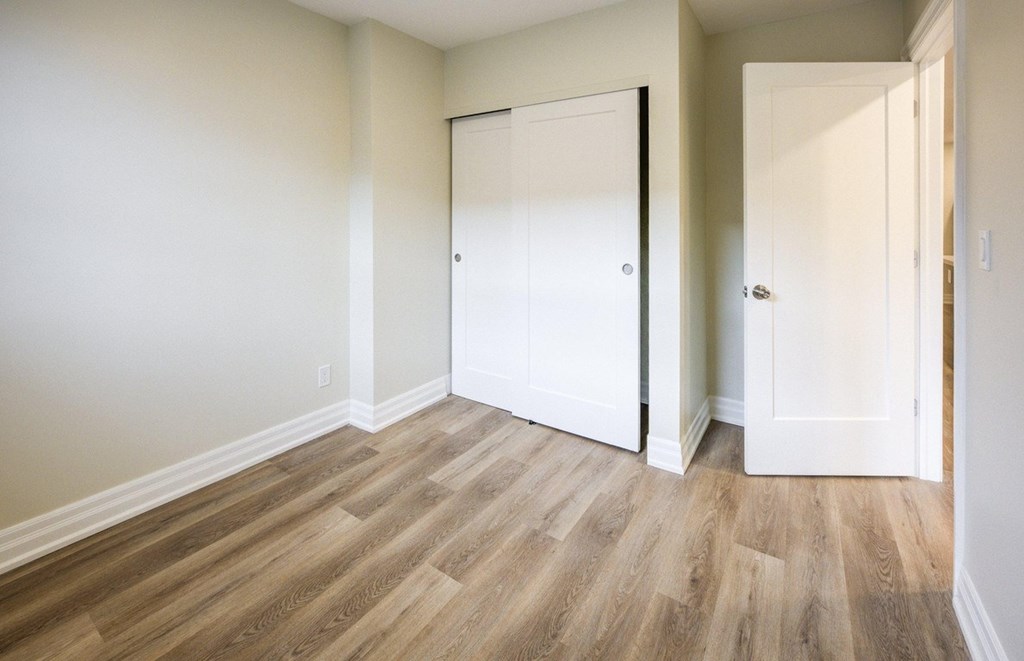 A room with a white door and a wooden floor.