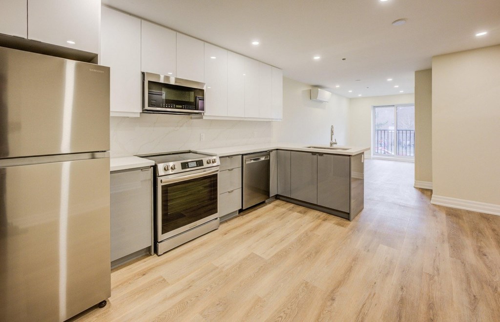 A modern kitchen with stainless steel appliances and wooden flooring.