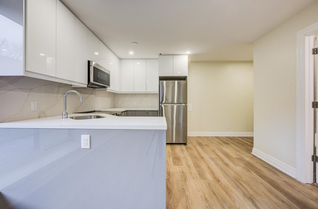 A kitchen with a white counter top and a stainless steel refrigerator.