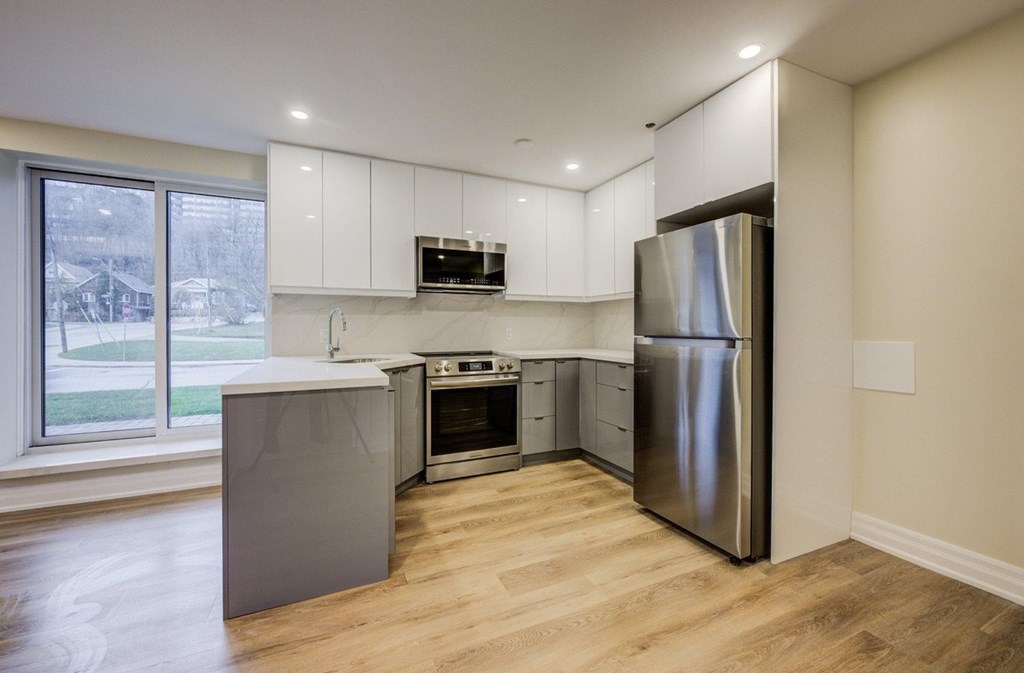 A kitchen with a refrigerator, oven, and microwave.