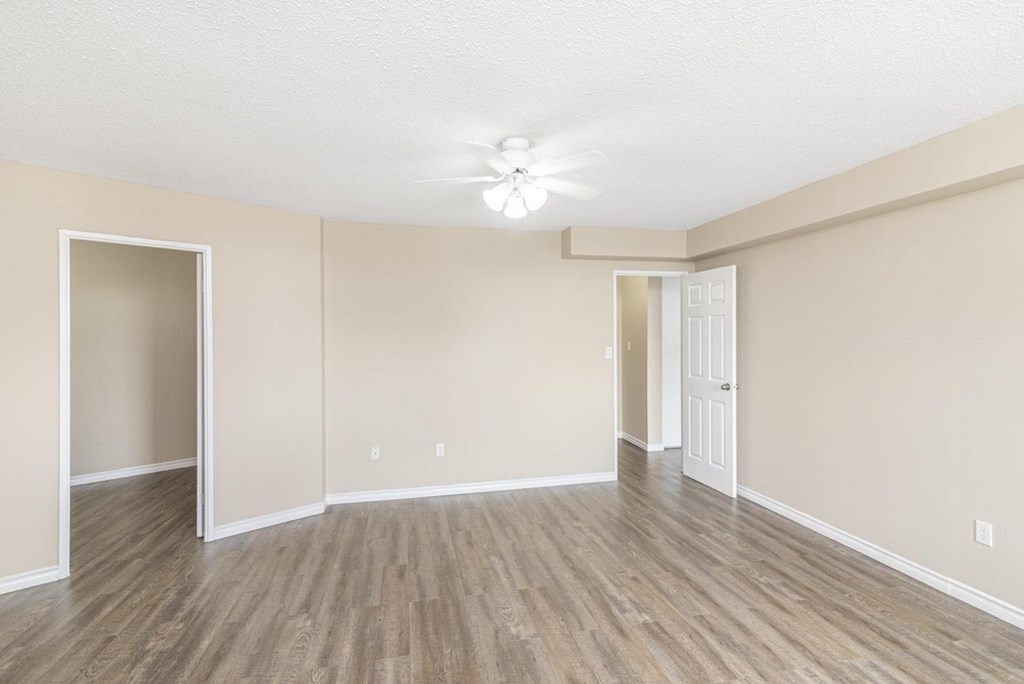 A room with a ceiling fan and light, and a door on the right.