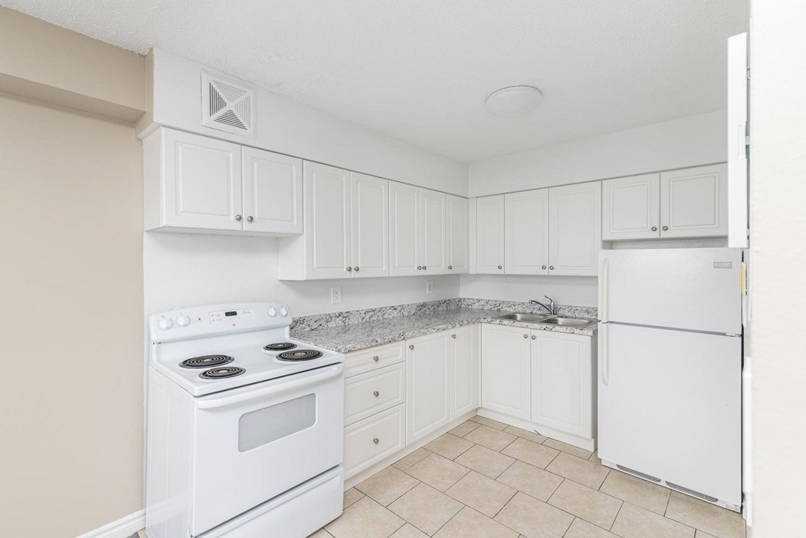 A white kitchen with a stove, sink, and refrigerator.