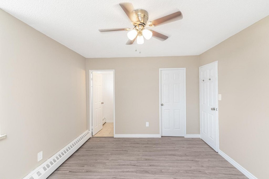 A room with a ceiling fan and two doors.
