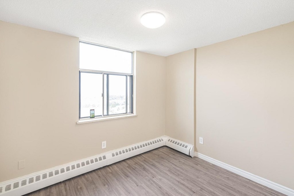 A room with a window and a radiator on the floor.