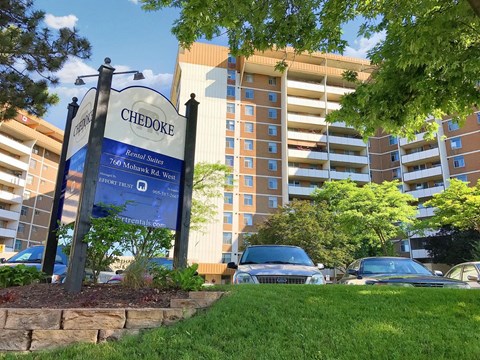 A sign for Chedoke Apartment Homes stands in front of a building.