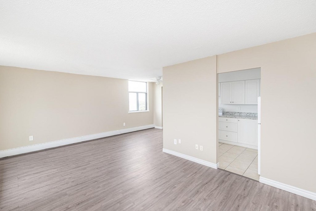 A room with a wooden floor and a wall with a window.