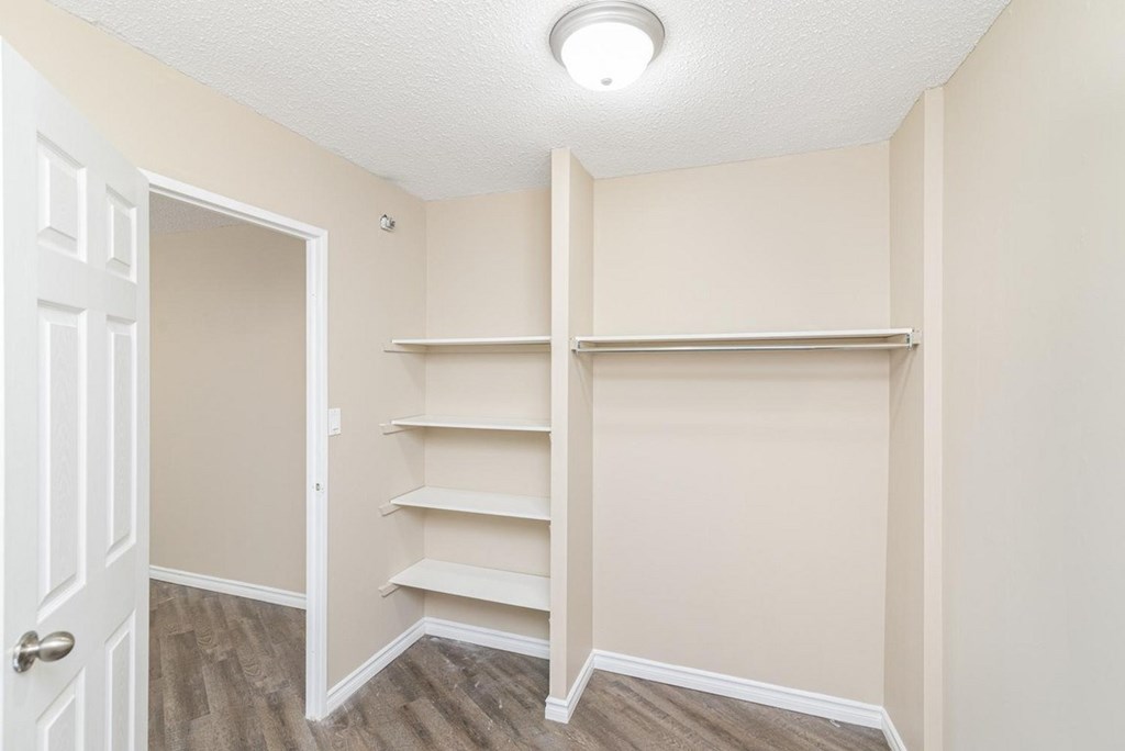 A room with a white door and shelves on the wall.