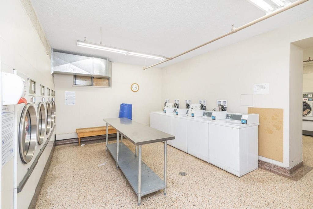 A laundromat with washers and dryers is shown.