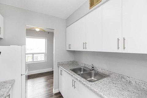 A kitchen with white cabinets and a granite countertop.