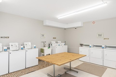 A room with a table in the middle and a wall with a sign that says Washer Dryer.