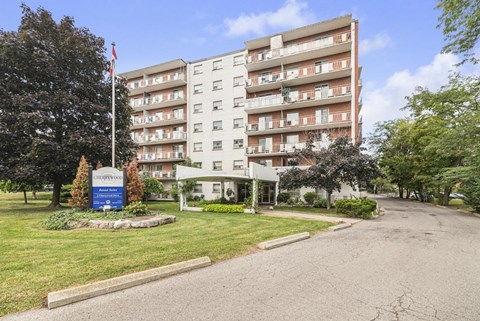 A large apartment building with a flag on top and a sign in front.