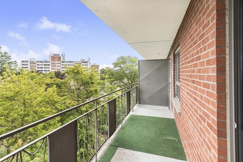 A balcony with a metal railing and a green carpet.