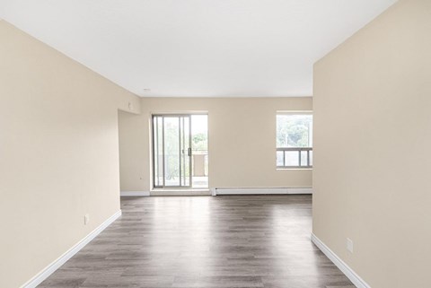 A large empty room with wooden floors and two windows.