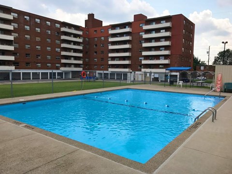 A large swimming pool in front of a red brick apartment building.