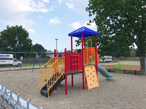 A playground with a red and yellow slide and a blue and yellow tower.