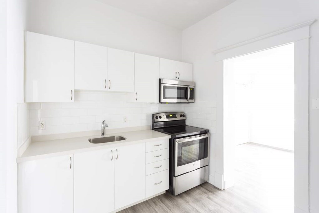 A white kitchen with a sink, microwave, and oven.