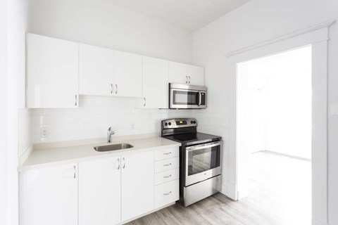 A white kitchen with a sink, microwave, and oven.