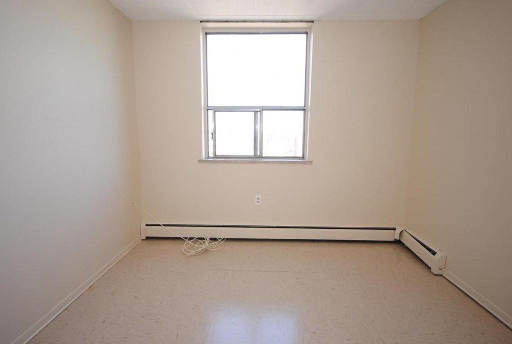 A room with a window and a radiator on the floor.