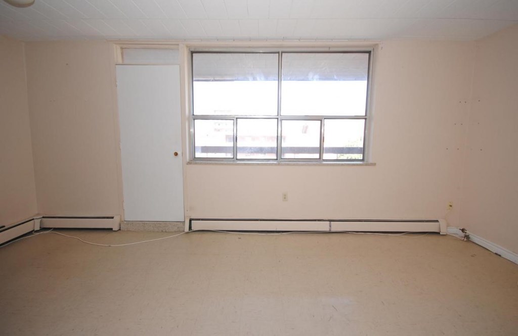 A room with a white door and a window with blinds.