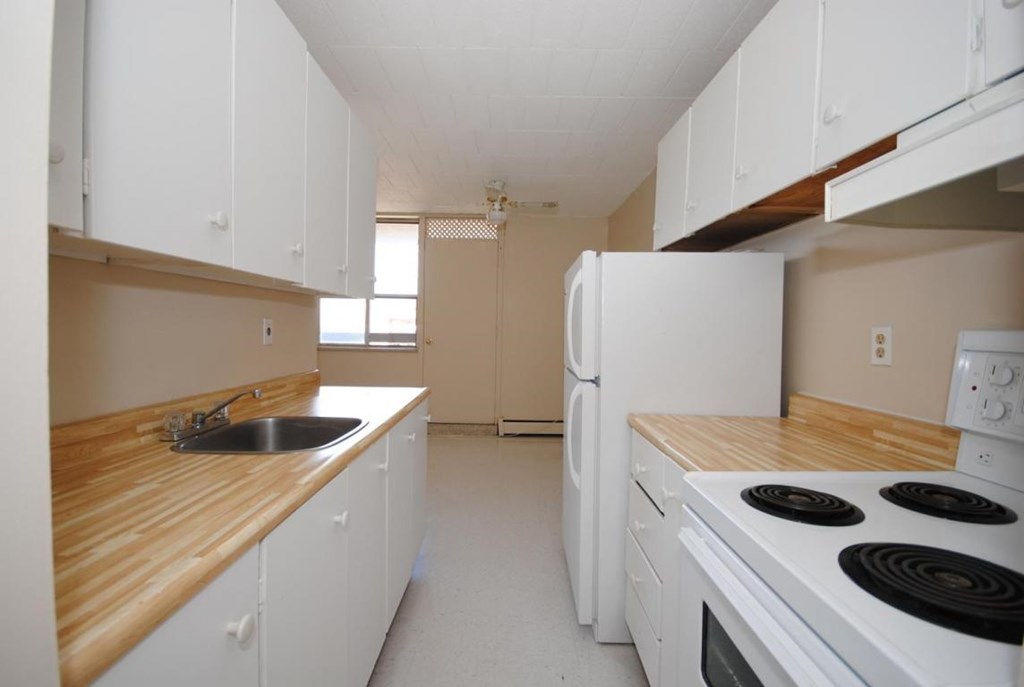 A kitchen with white cabinets and a wooden counter top.