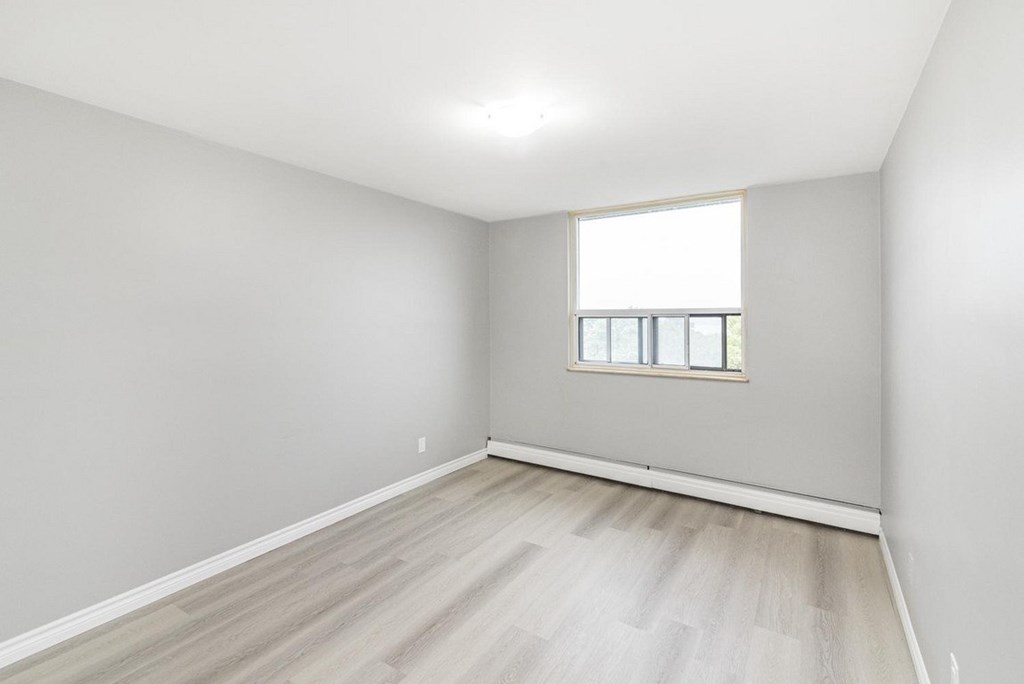 A room with a window and wooden flooring.
