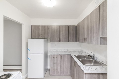 A kitchen with a white fridge and a marble counter top.