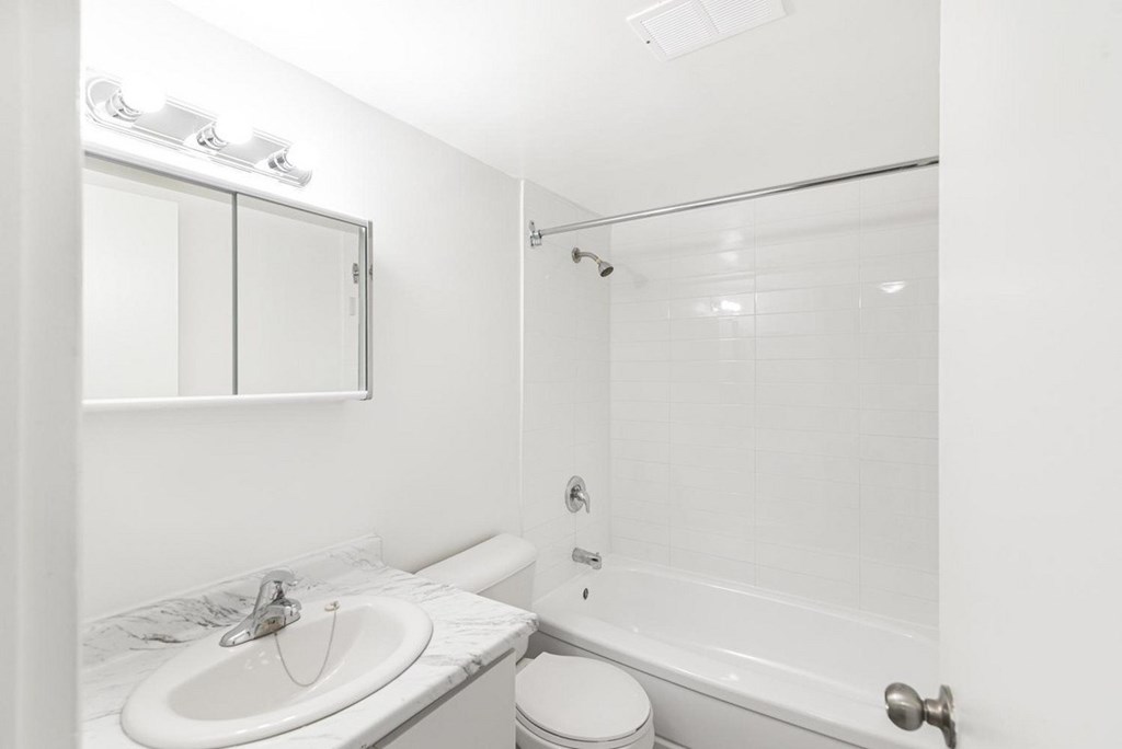 A white bathroom with a toilet, sink, and bathtub.