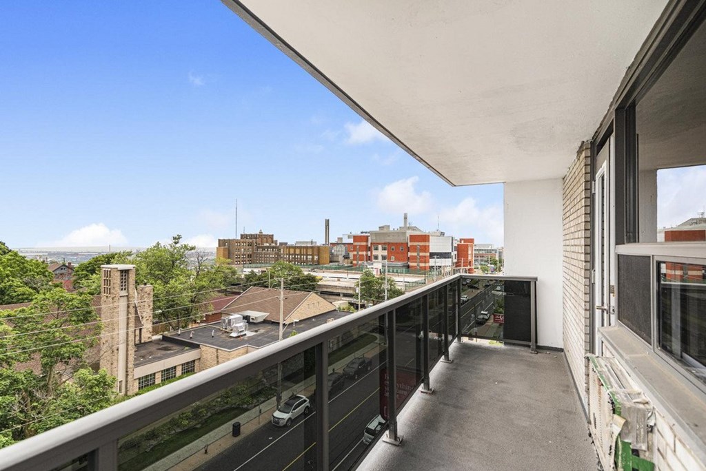 A balcony with a black railing overlooks a cityscape.