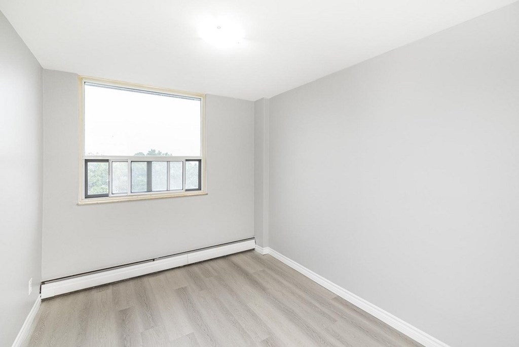 A room with a window and wooden flooring.