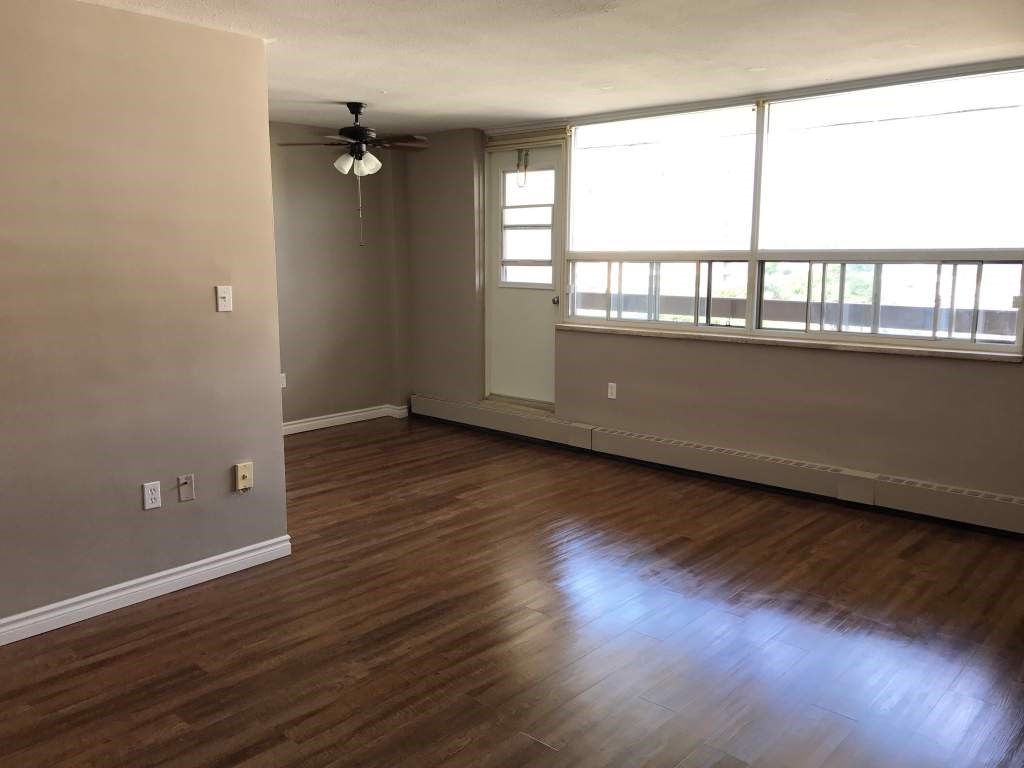 A room with wooden flooring and a window with blinds.