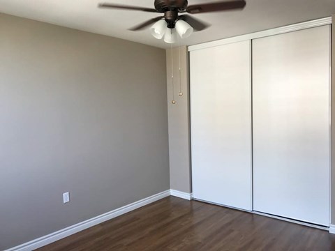 A room with a ceiling fan and a white closet.