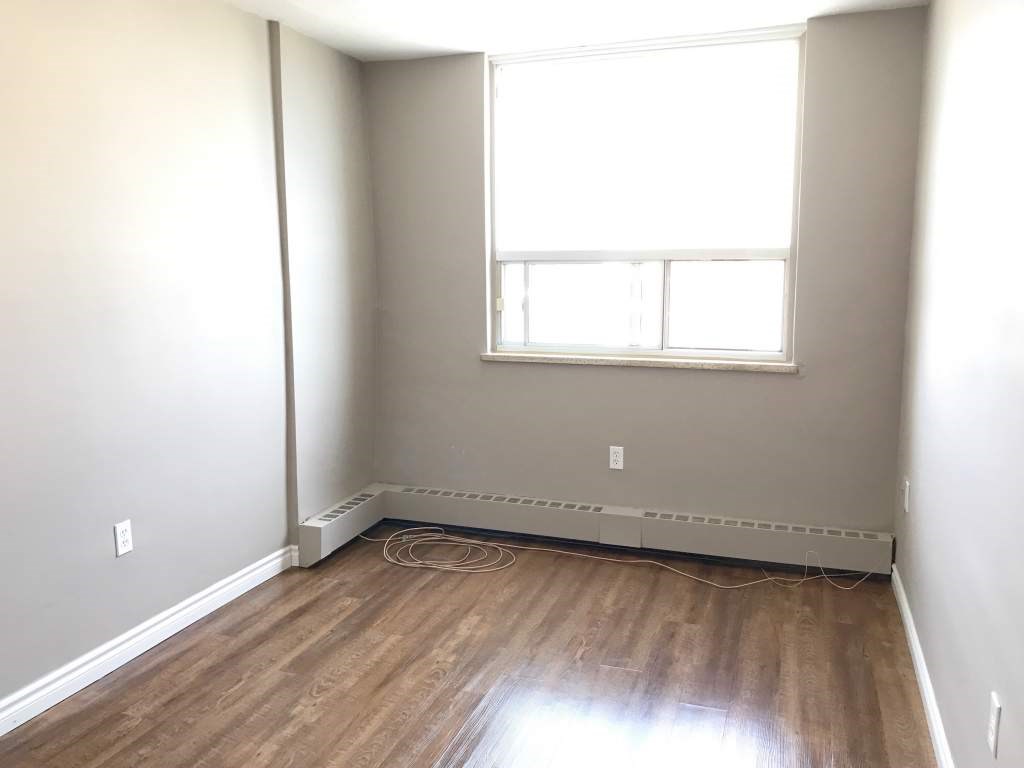 A room with a window and a radiator on the floor.