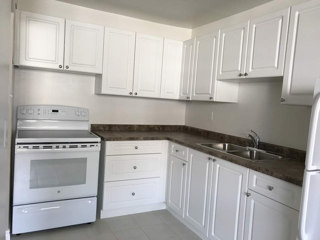 A kitchen with white cabinets and a stainless steel oven.