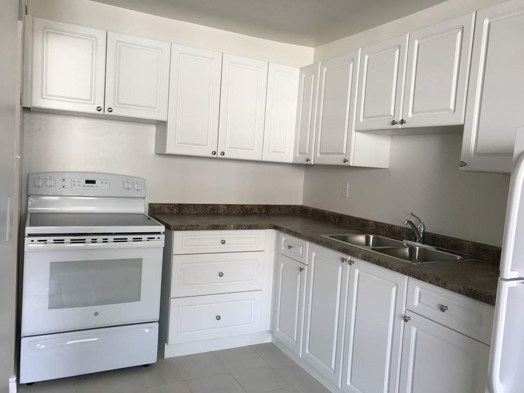 A kitchen with white cabinets and a stainless steel oven.
