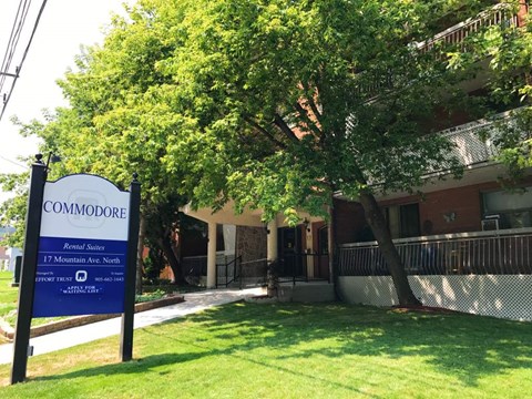 A sign for Commodore Apartment Homes stands in front of a building.