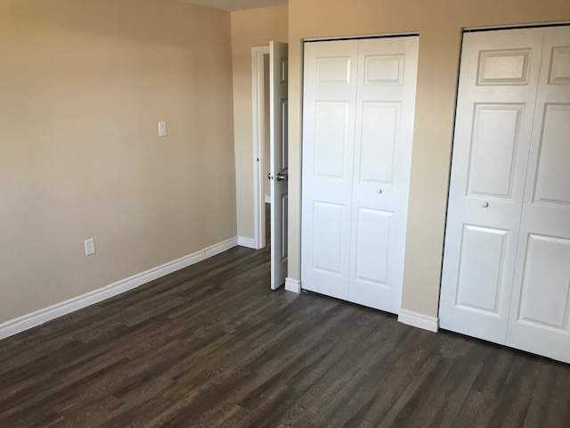 A room with a white door and a brown floor.