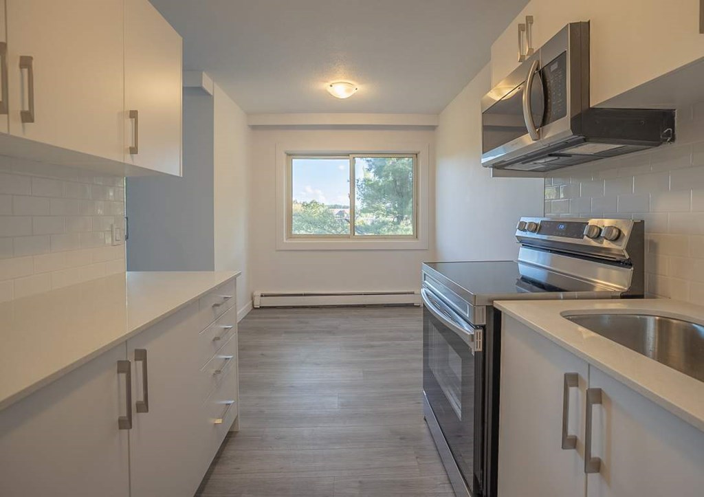 A kitchen with white cabinets and a black microwave above the stove.