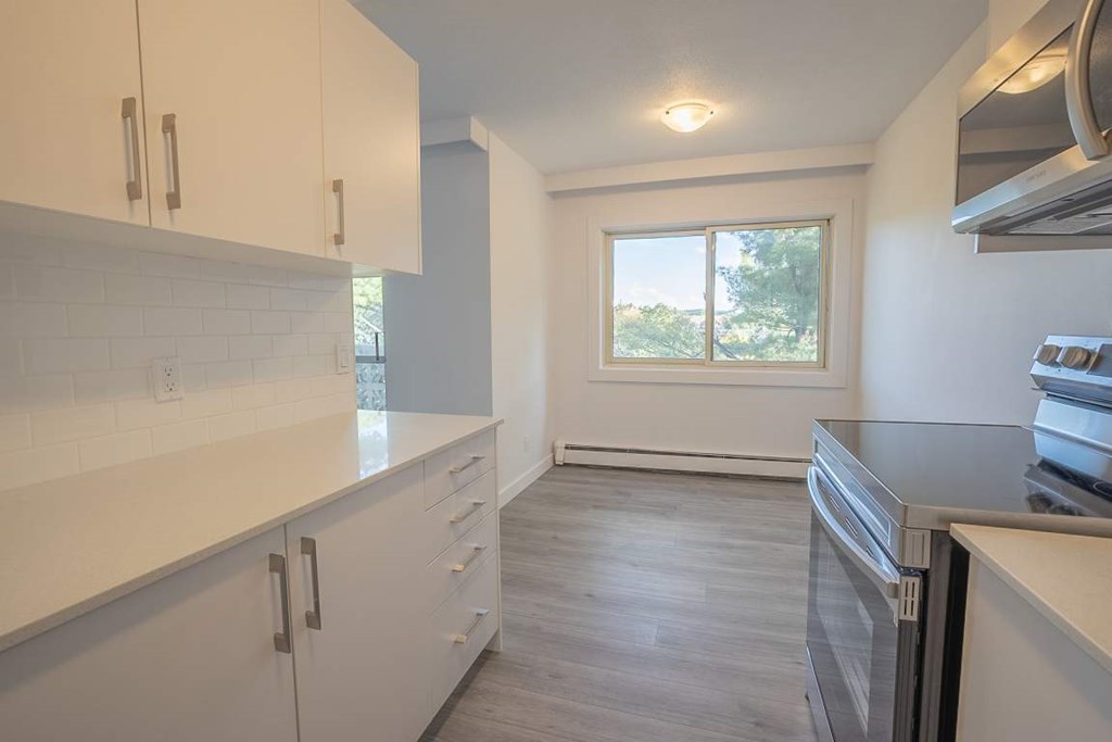 A kitchen with white cabinets and a window.