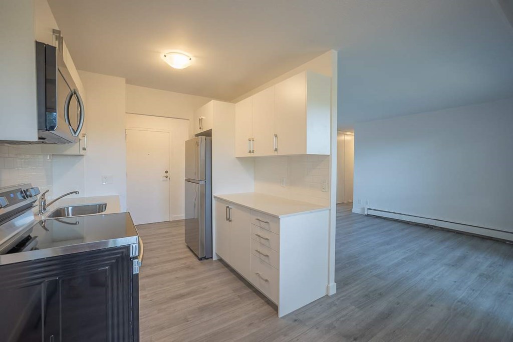 A kitchen with a refrigerator, sink, and cabinets.