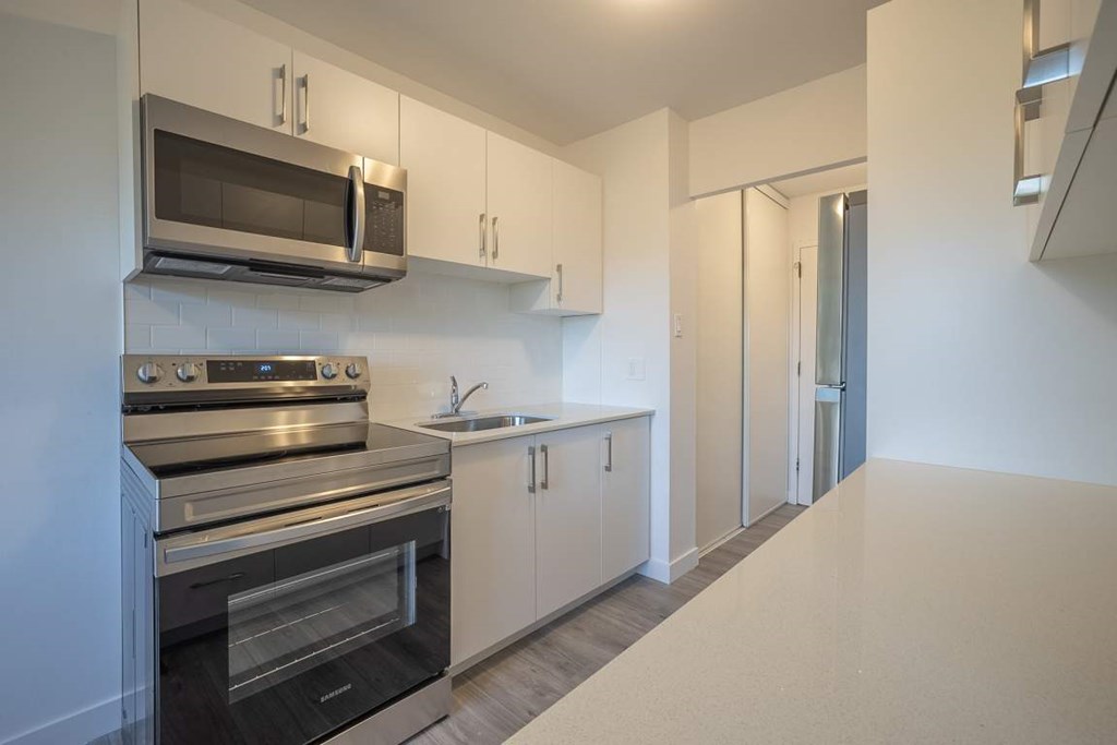 A modern kitchen with stainless steel appliances and white cabinets.