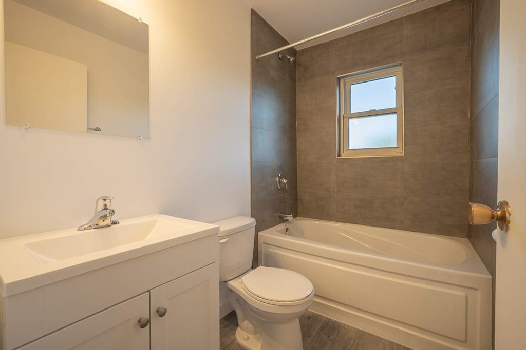 A white toilet sits next to a bathtub in a bathroom.