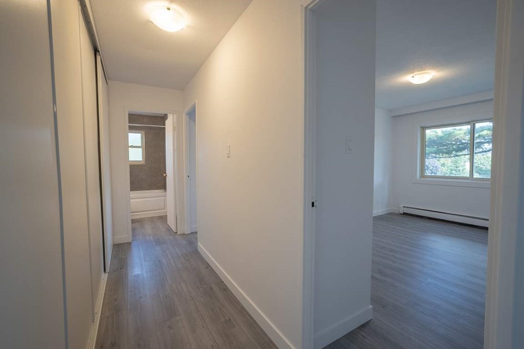 A long hallway with wood floors and white walls.