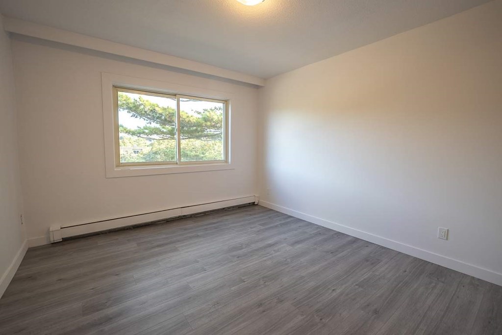 A room with a window and wooden flooring.