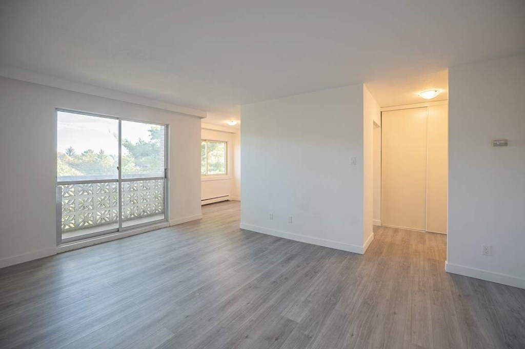 A spacious room with a sliding glass door leading to a balcony.