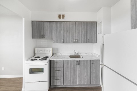 A white stove and sink in a kitchen with grey cabinets.