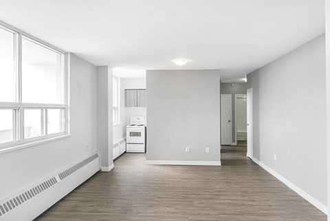A spacious, empty room with a window on the left and a white appliance in the middle.