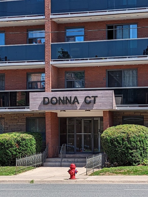 A red fire hydrant is in front of a building named Donna Court.